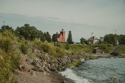 Idyllic lighthouse on Lake Superior's rocky shore in Duluth, Minnesota, surrounded by lush greenery.