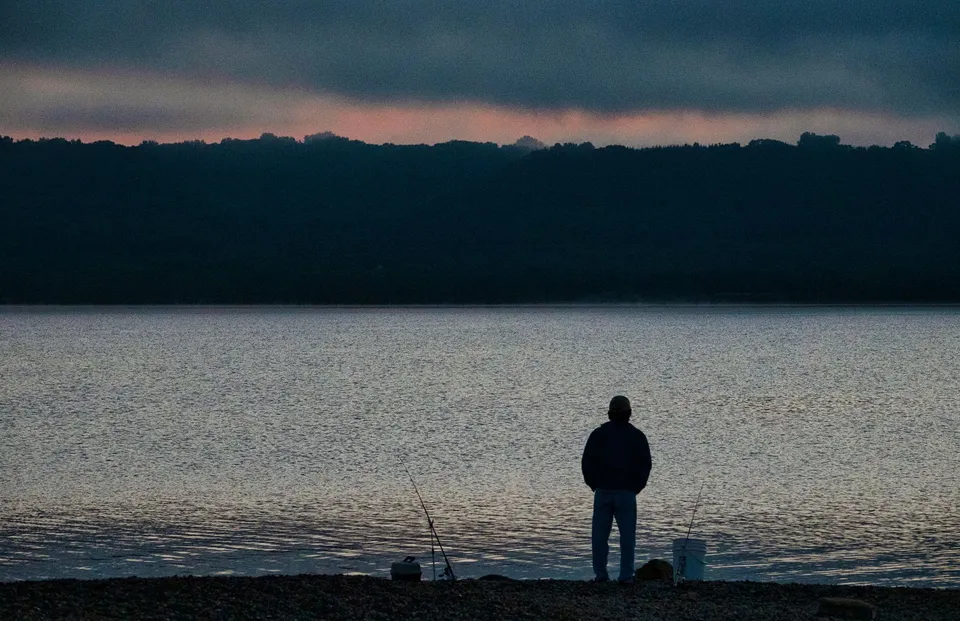 A solitary fisherman by Lake Pepin at dawn, capturing a serene fishing moment.