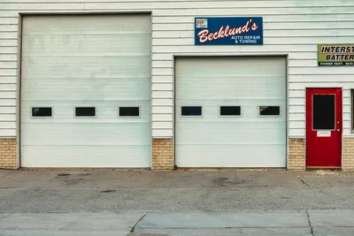 Front view of an auto repair shop with roll-up doors and signage in Millville, Minnesota.